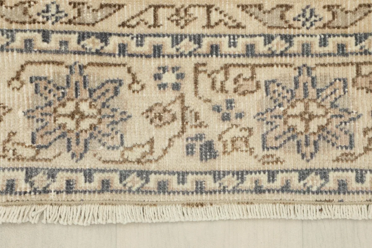 Close-up of the rug's border and fringe, revealing the hand-knotted wool pile and cotton foundation.