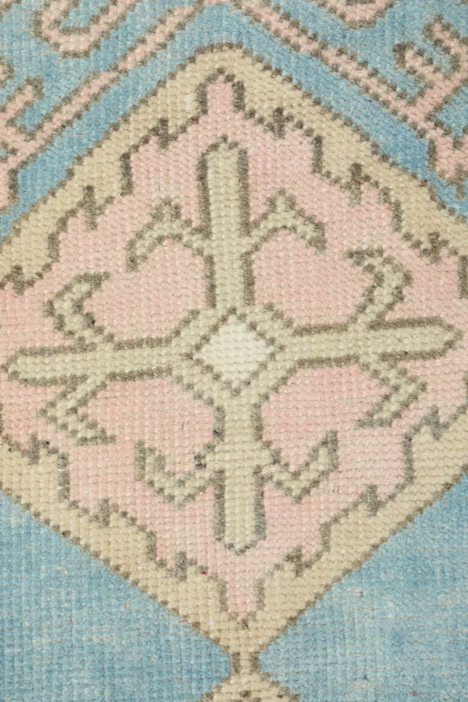 Close-up of a pink diamond motif with subtle details within the rug's pattern