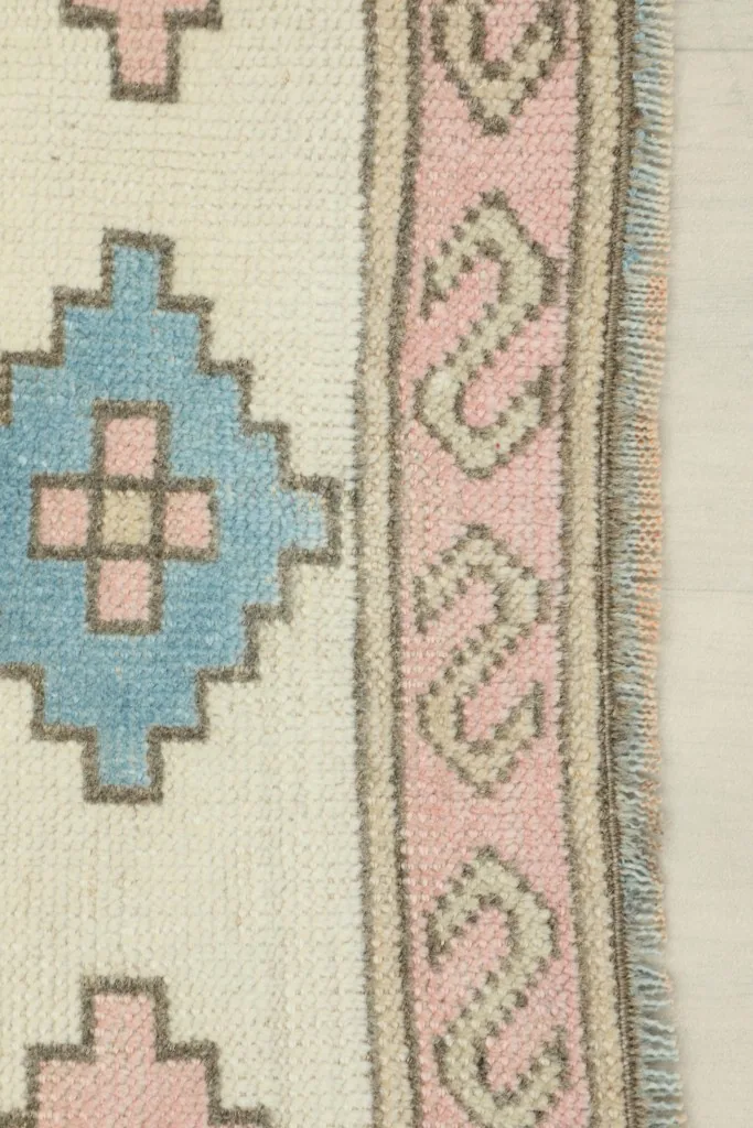 Detailed view of the outer pink border with a wavy pattern and blue diamond motifs