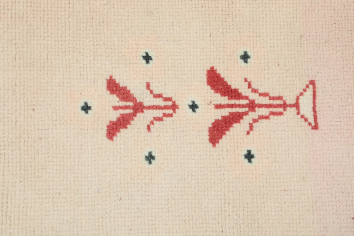 Detailed close-up of the hand-knotted red and green floral motif and small charcoal dots