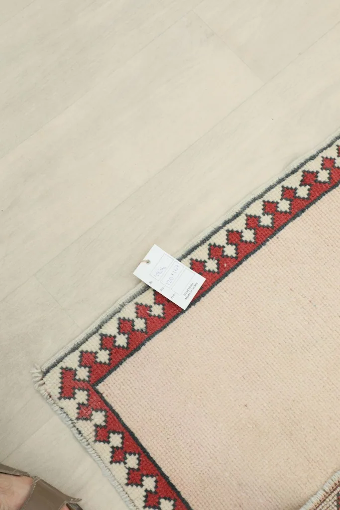Underside of the rug with a label, showing the tightly woven cotton foundation and knotting