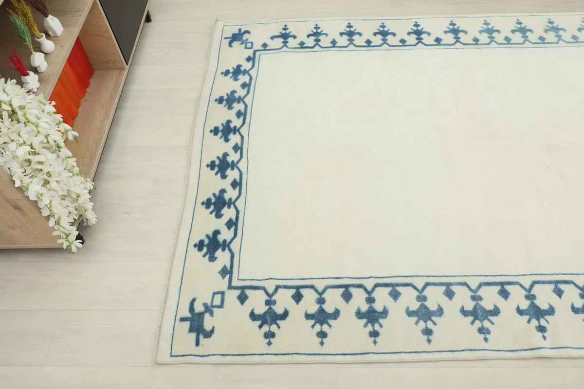 Another angle shot of the rug, detailing the border pattern and soft ivory color