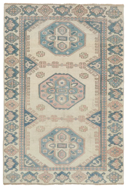 Full top view of the 4'11" x 7'3" vintage Anatolian rug with ivory, blue, and pink geometric patterns.