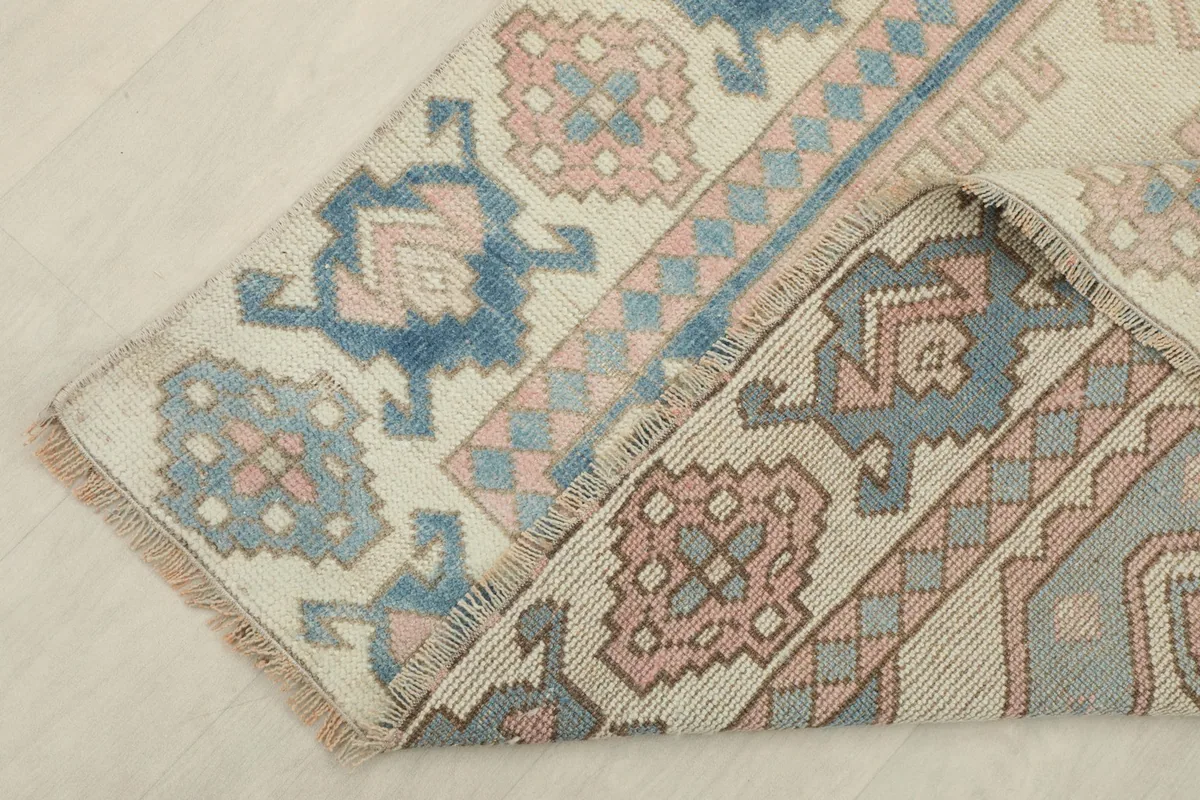 Corner of the rug folded to reveal the cotton foundation and the reverse side of the hand-knotted construction.