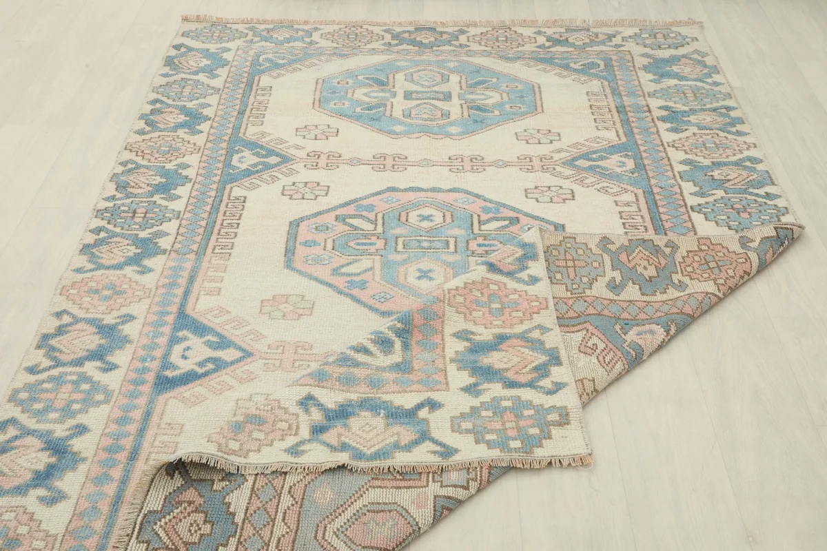 Rug partially folded over itself, showing the full design and the flexibility of the vintage wool material.