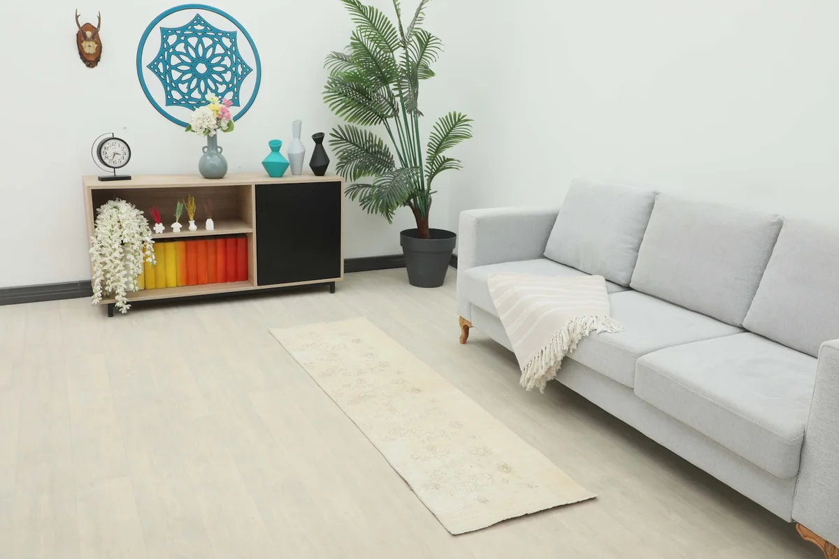 Runner rug placed in a modern living room setting, showcasing its scale and cream tones.