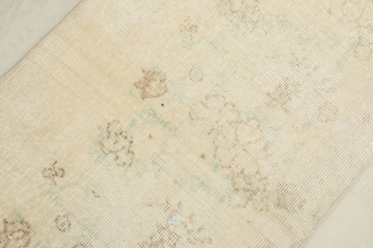 Macro shot of the rug's surface, showing the variations in cream and tan colors and wool texture.