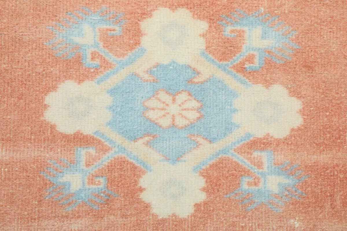Close-up of a single geometric motif within the rust field, showing beige and blue details.