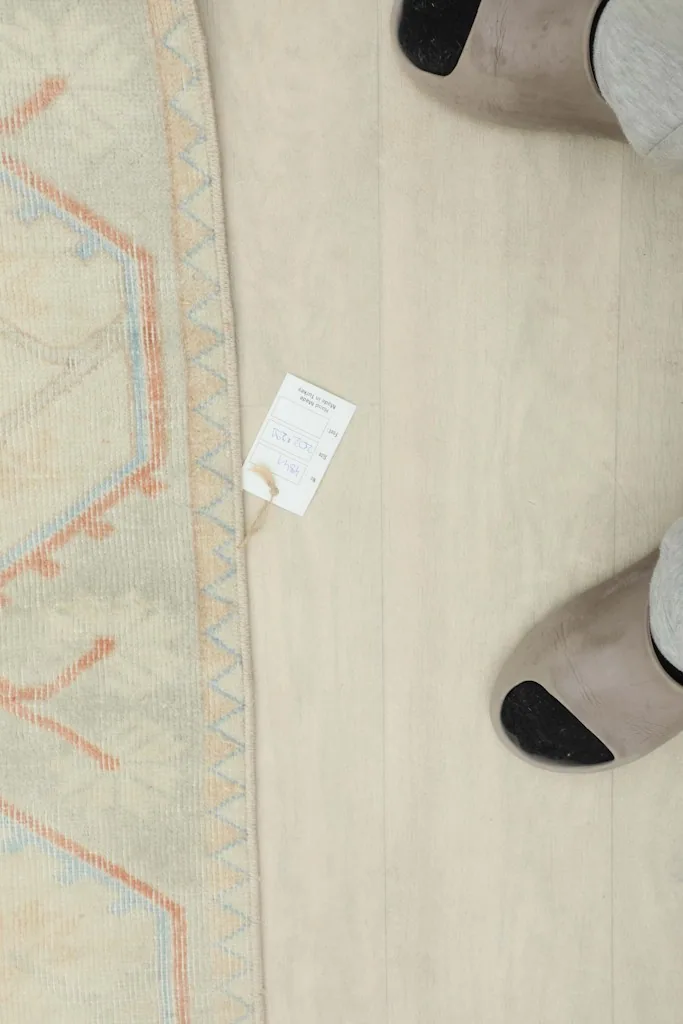Overhead view of a corner of the rug with a tag, showing the low pile and texture.