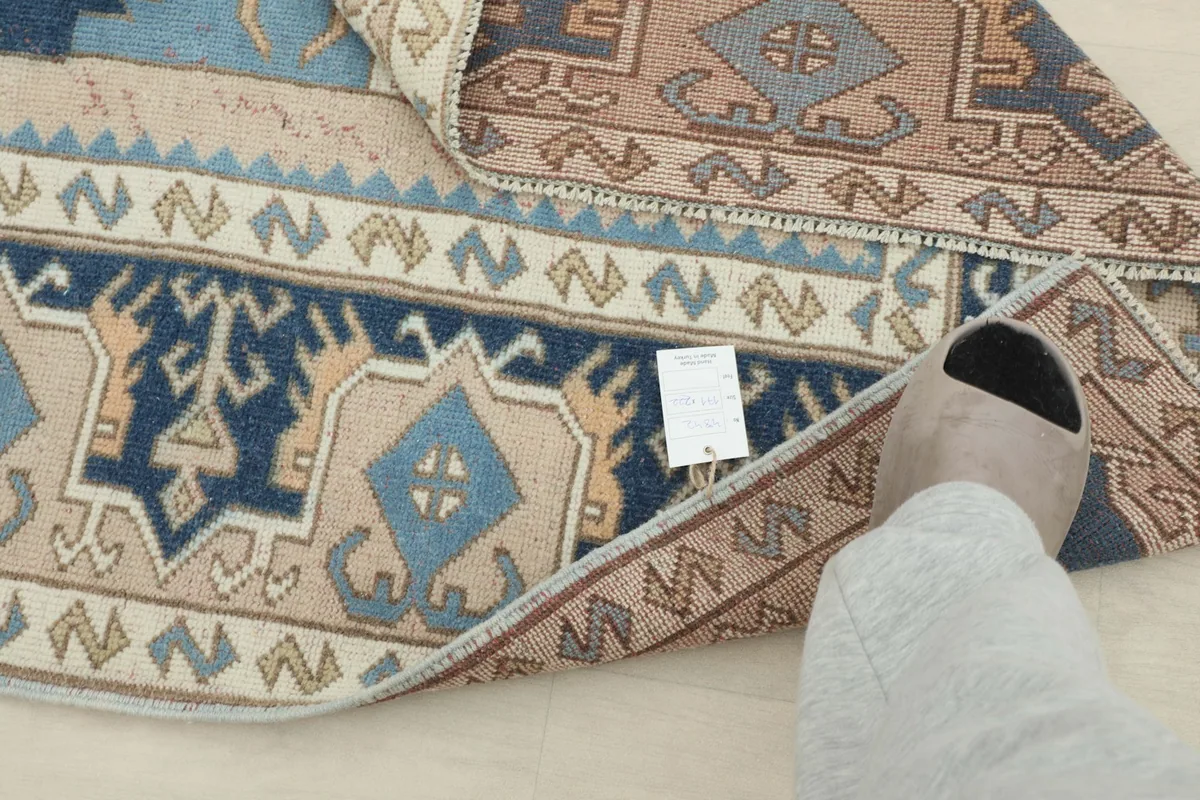 View of the rug's reverse side and structure, with a small tag visible
