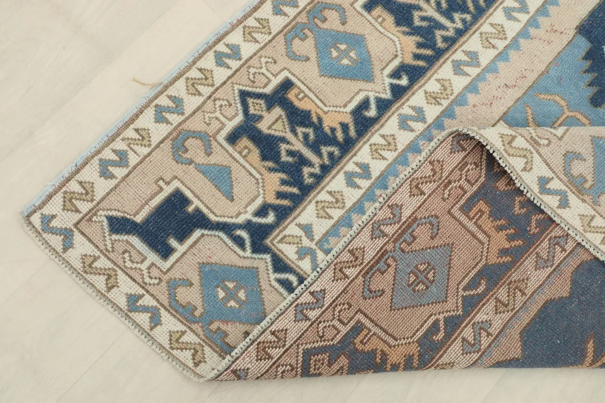 Folded corner of the rug, showing the reverse side and the cotton foundation