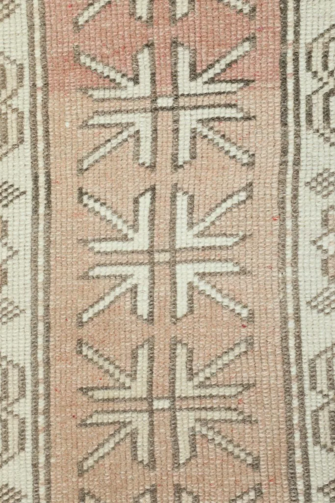 Detailed close-up of the hand-knotted wool pile and geometric motifs in the central rose stripe