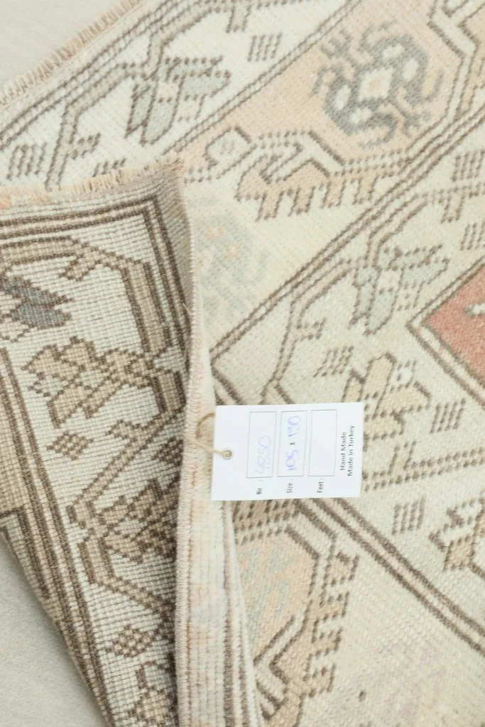 Partial view of the rug with a size tag, showing the reverse side and hand-knotted details
