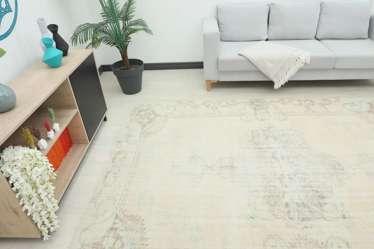 Overhead angle of the cream vintage rug in a room, showing its scale next to a sofa and cabinet