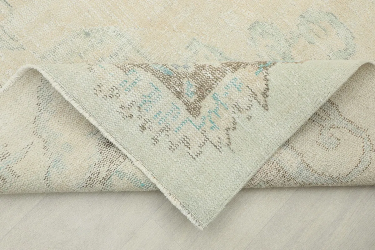 Folded corner of the rug revealing the tightly hand-knotted wool pile on a cotton foundation
