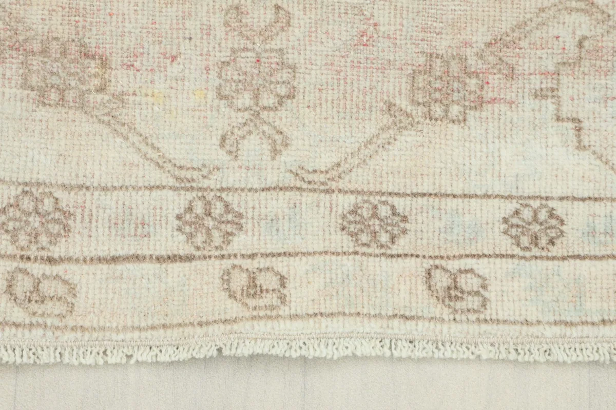 Close-up of the rug's border, showing intricate beige geometric patterns and the low pile texture.