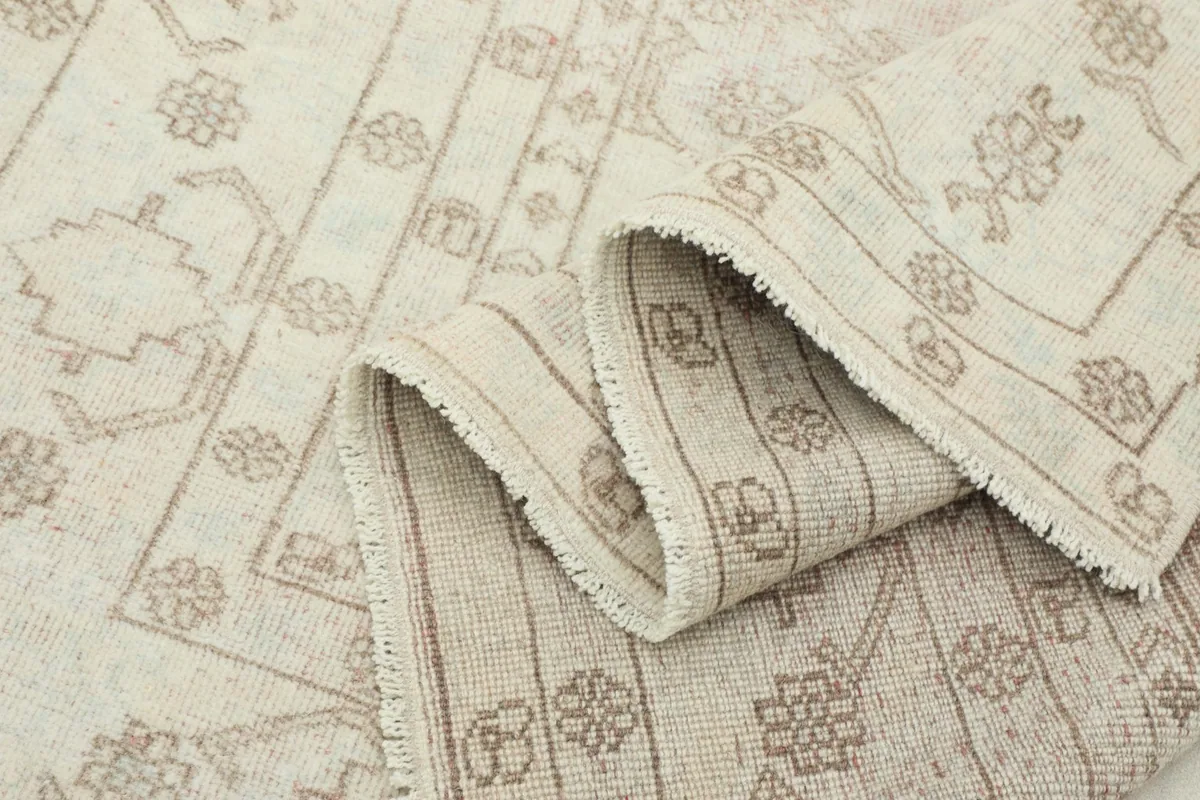 Close-up of the rug's low pile and the subtle variations in the beige and ivory wool fibers.