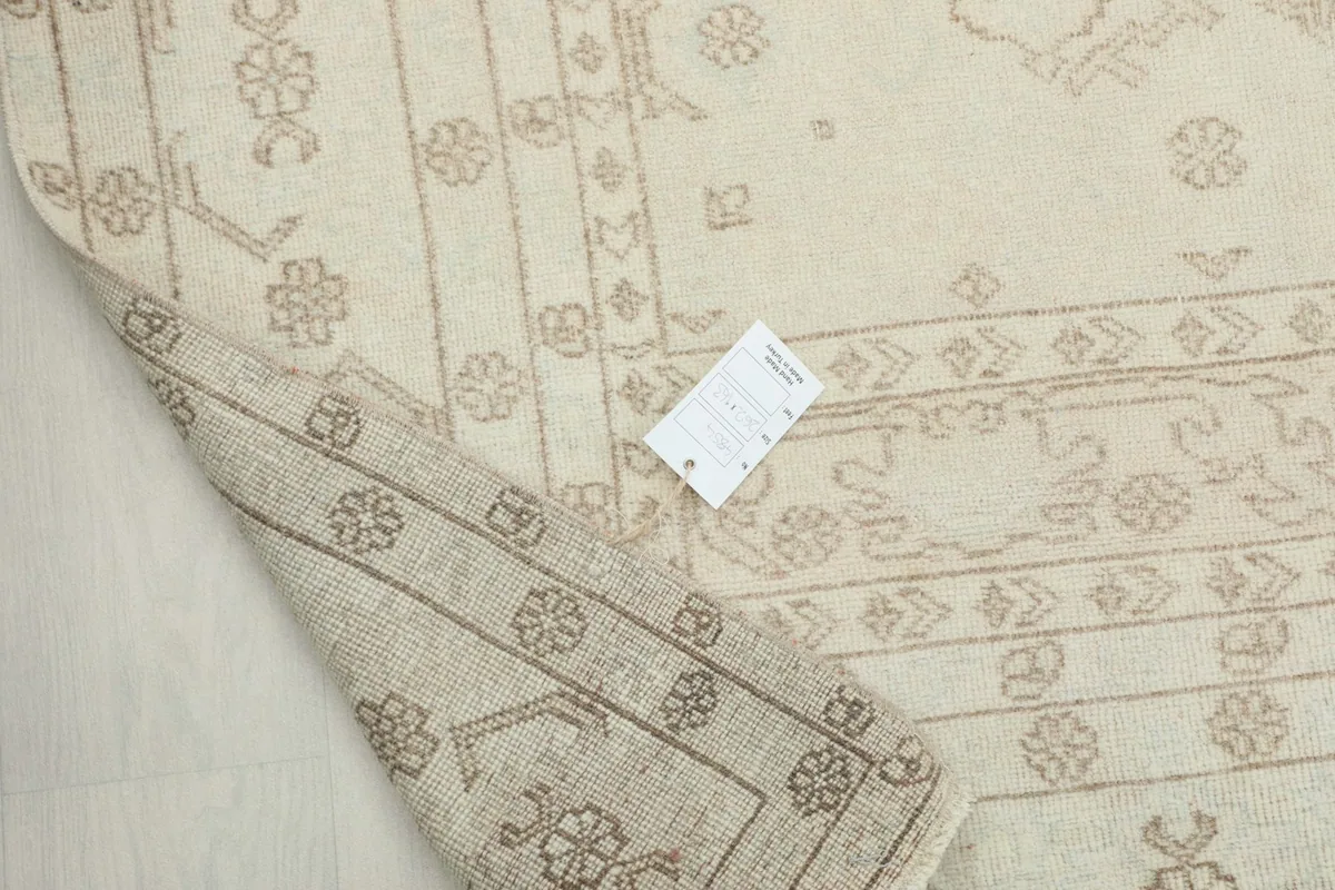 Corner of the rug turned over, showing the tightly woven cotton foundation and the reverse of the patterns.