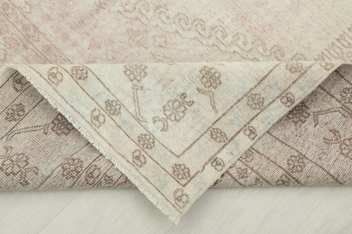 Folded corner of the rug, showing the back of the hand-knotted wool pile on cotton foundation.