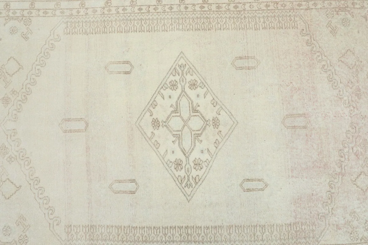 Overhead view highlighting the central beige medallion and subtle geometric details on the ivory background.