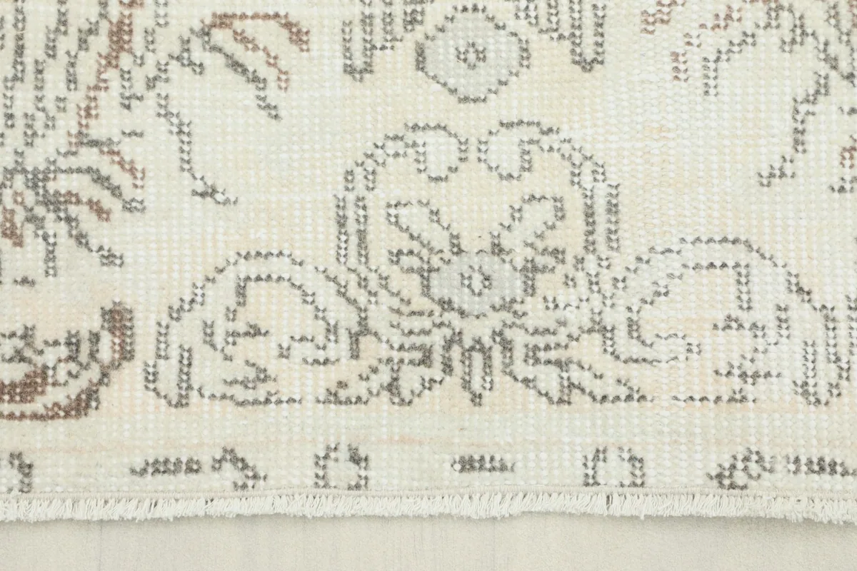 Close-up of the rug's short fringe and subtle wear on the ivory and gray pattern
