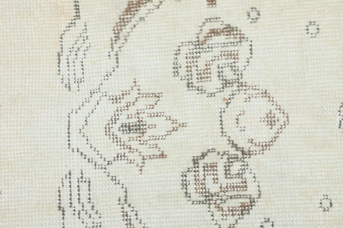 Detailed view of the hand-knotted wool pile and intricate gray and tan botanical patterns
