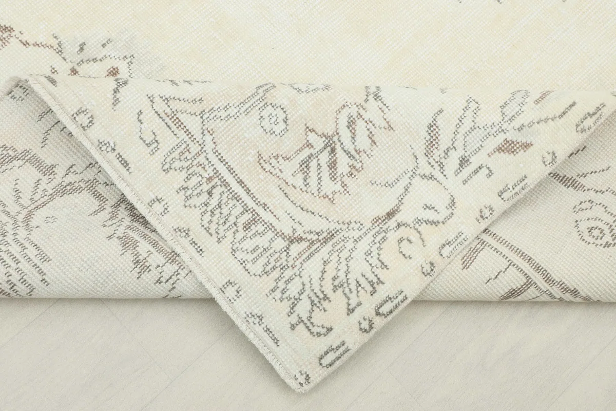 Folded corner of the rug revealing the cotton foundation and reverse side of the pattern