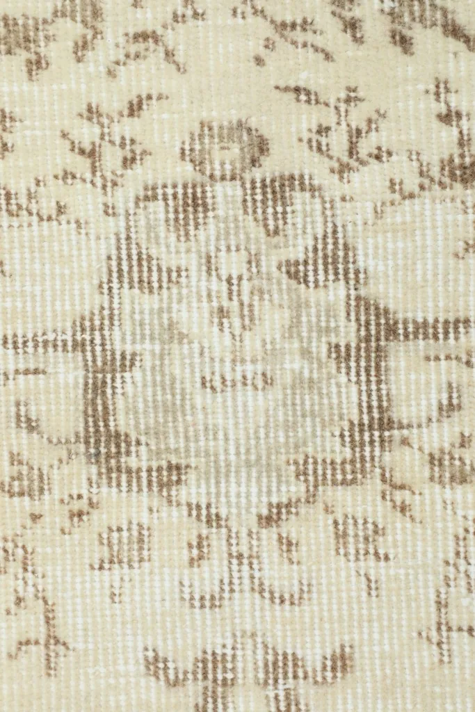 Close-up of the intricate hand-knotted wool fibers and faded beige patterns.