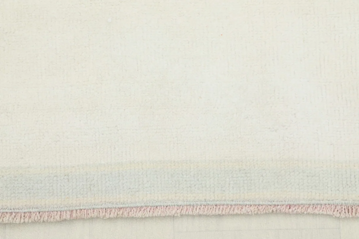 Close-up view of the low pile texture and subtle color variations of the rug's ivory field