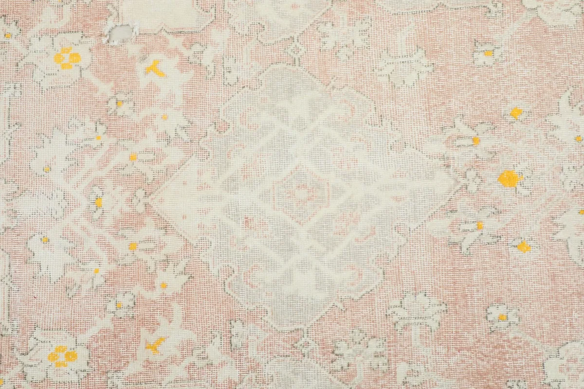 Detailed view of the central medallion and floral patterns in rose, ivory, and yellow.