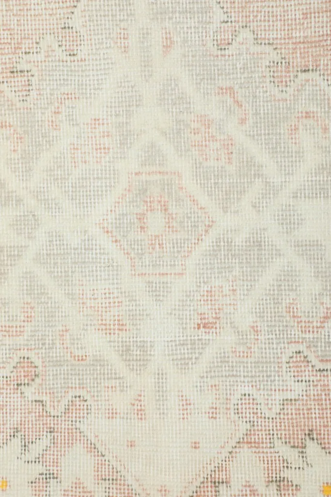 Close-up of the low wool pile, showing the texture and muted colors of the vintage rug.