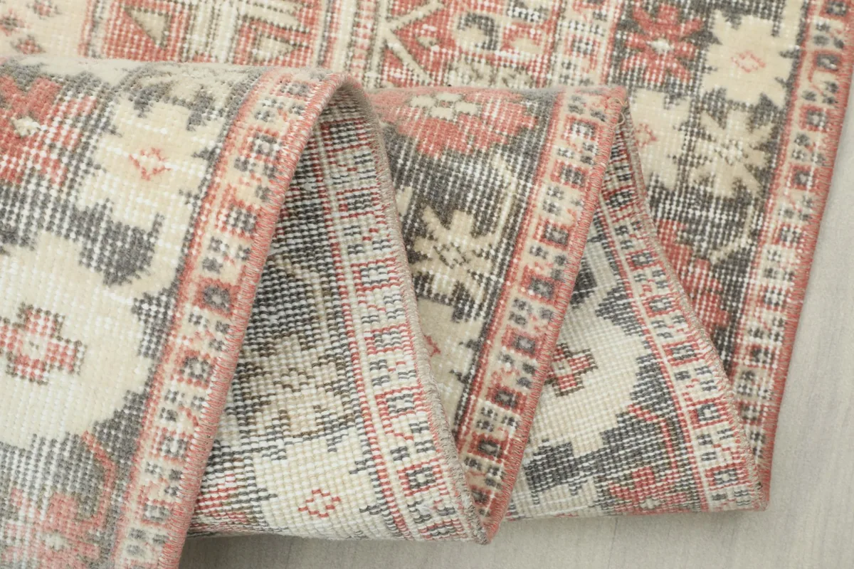 Close-up of the rug folded, showing the intricate border design and wool pile texture
