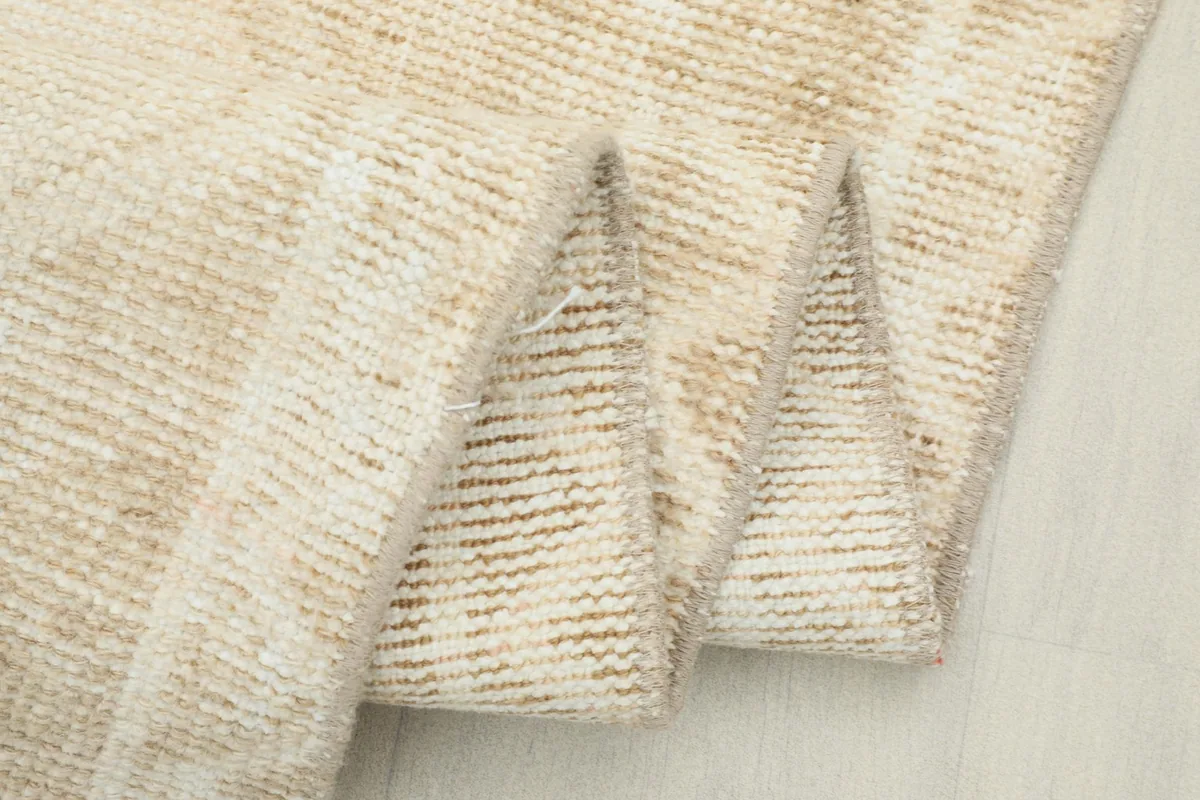 Close-up of the rug folded, revealing the tight hand-knotted construction and cotton foundation