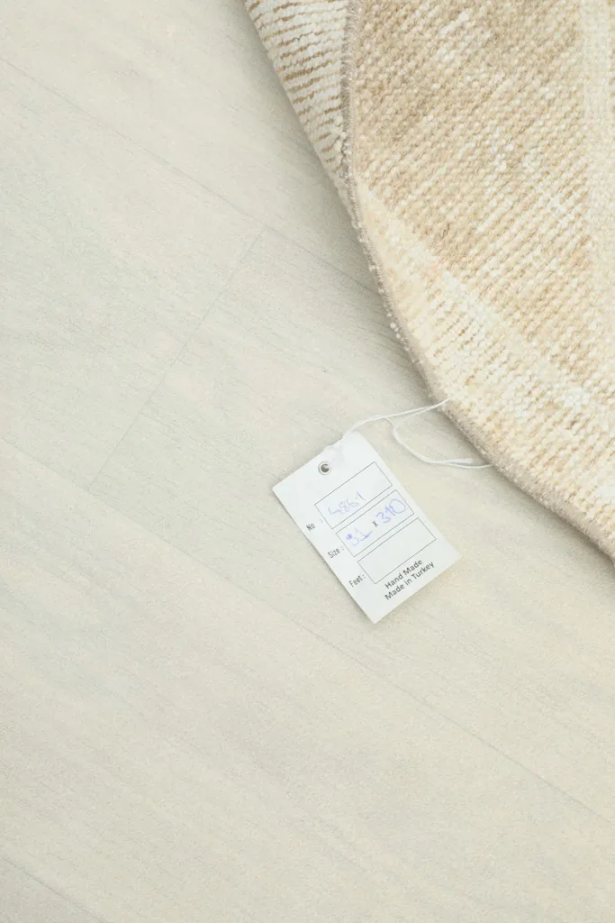 Corner of the rug with its product tag visible on a light floor, showing rug details
