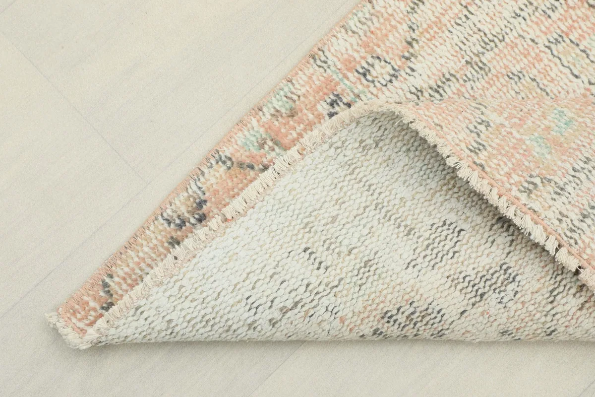 Corner of the rug folded to show the cotton foundation and reverse side
