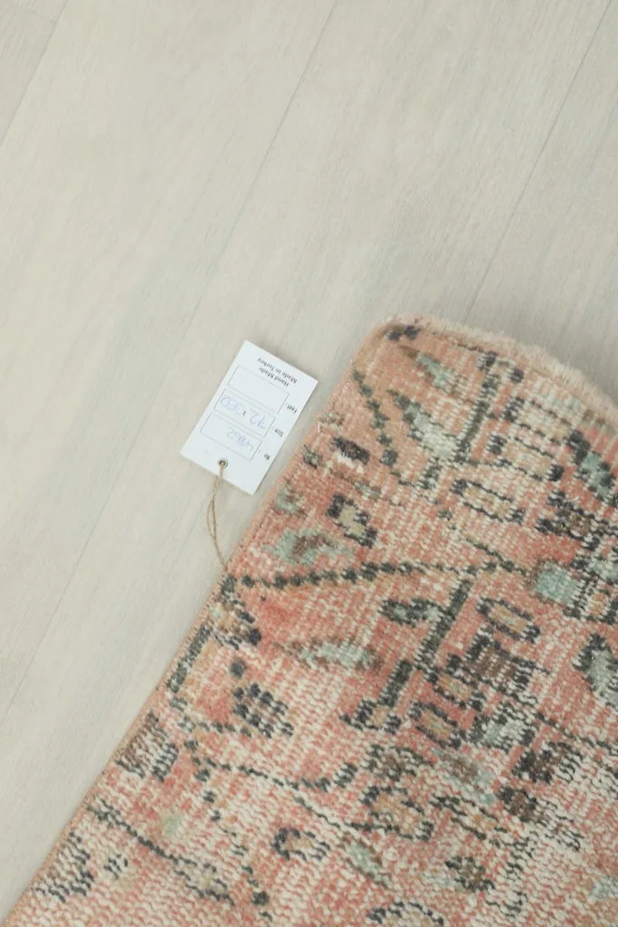Corner of the rug with its product tag, showing the natural fringe