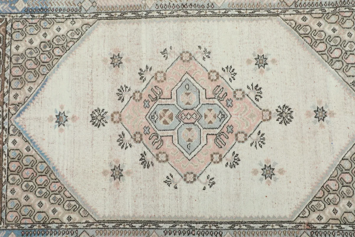 Overhead view focusing on the central ivory field and the rose and blue medallion design.