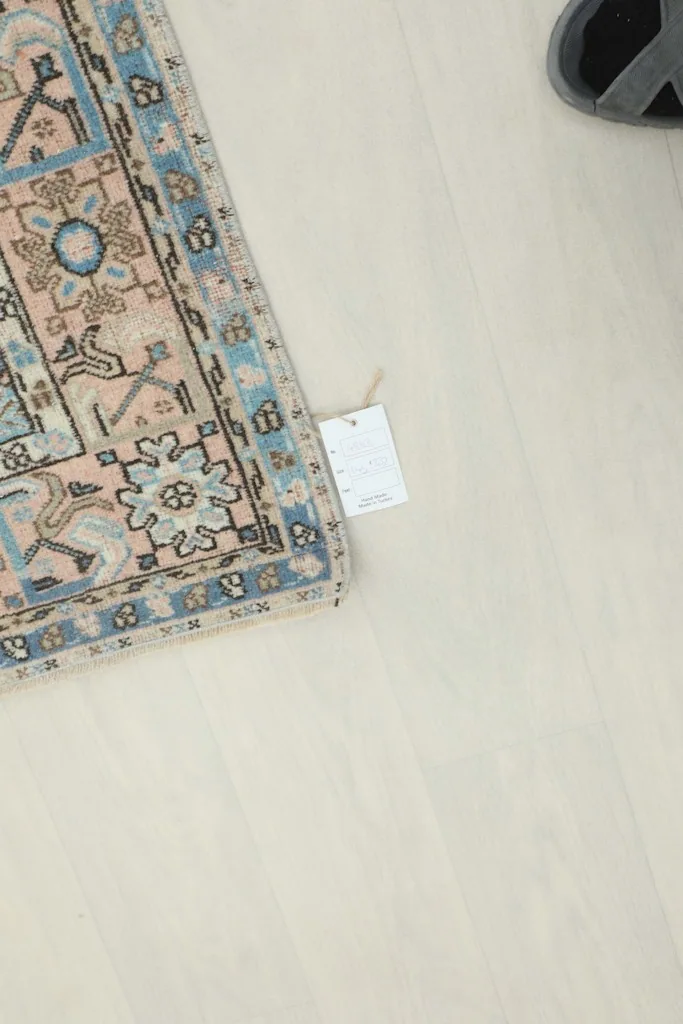 Top-down view of a corner of the rug, showing a small product tag and the floor.