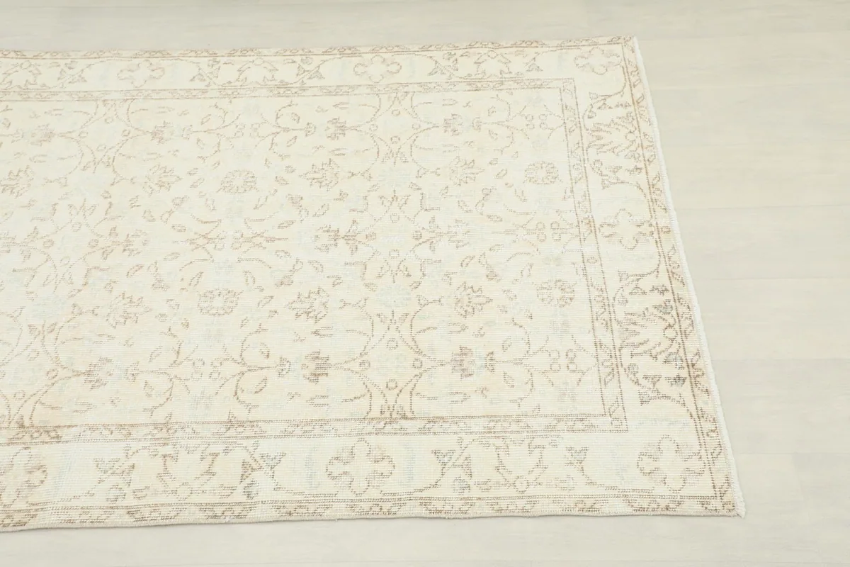 Close-up corner view of the ivory and beige floral pattern and border of the vintage Anatolian rug