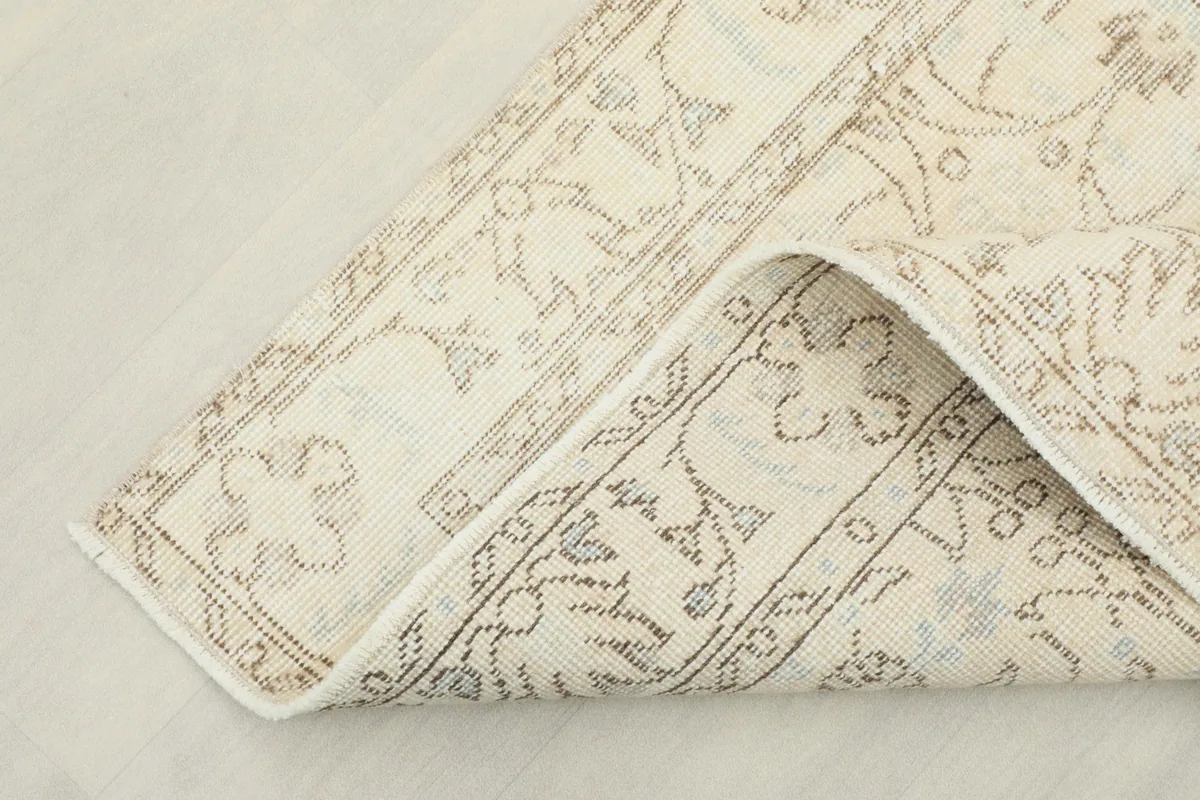 Corner of the ivory and beige vintage Anatolian rug folded to show the backing and construction