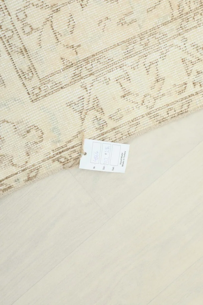 View of the rug with a label, showing the product information on the ivory and beige vintage Anatolian rug