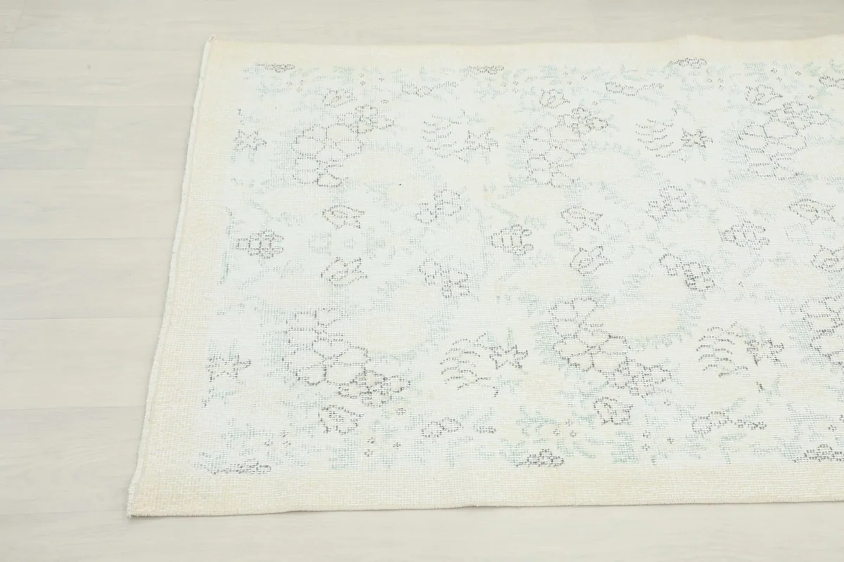 Another corner view of the rug, showing the faded ivory field and pattern.