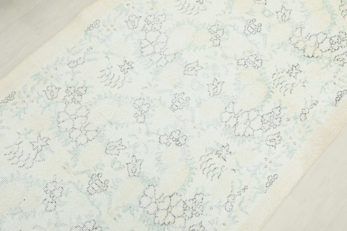 Close-up of the rug's surface, showing the faded floral and geometric motifs.