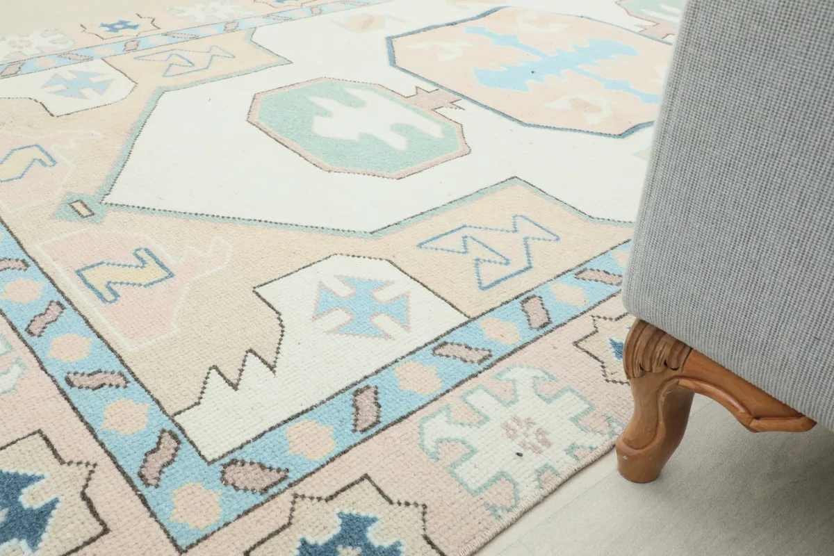 Angled view of the rug in a room, with a sofa leg in the foreground, showing scale