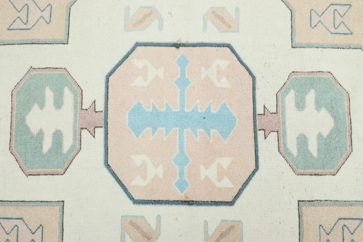 Detailed view of the central geometric medallion with rose and blue patterns on an ivory field