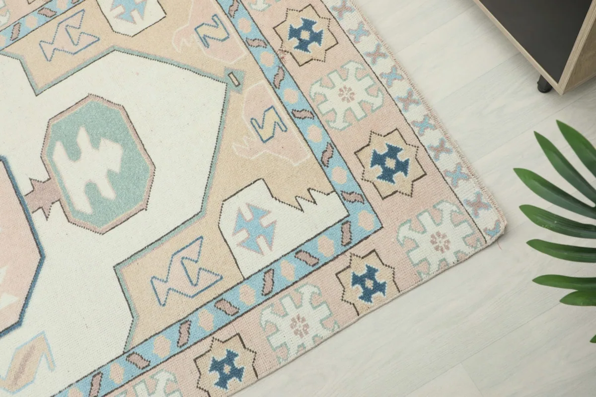 Close-up of the rug's border and corner, highlighting the geometric patterns and soft colors