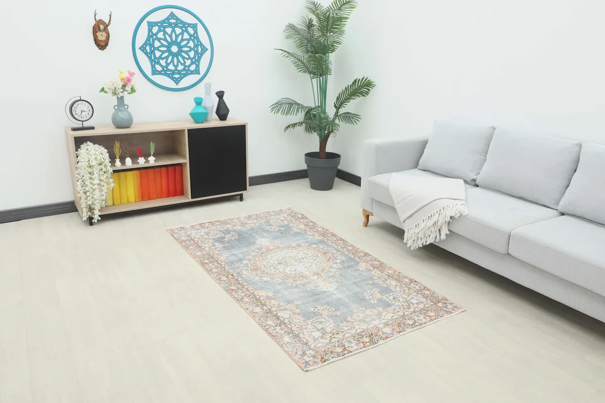 Vintage gray and orange rug in a living room setting with a sofa and side table