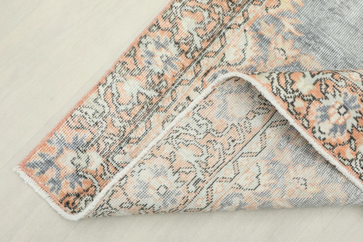 Corner of the rug folded back to show the cotton foundation and reverse side