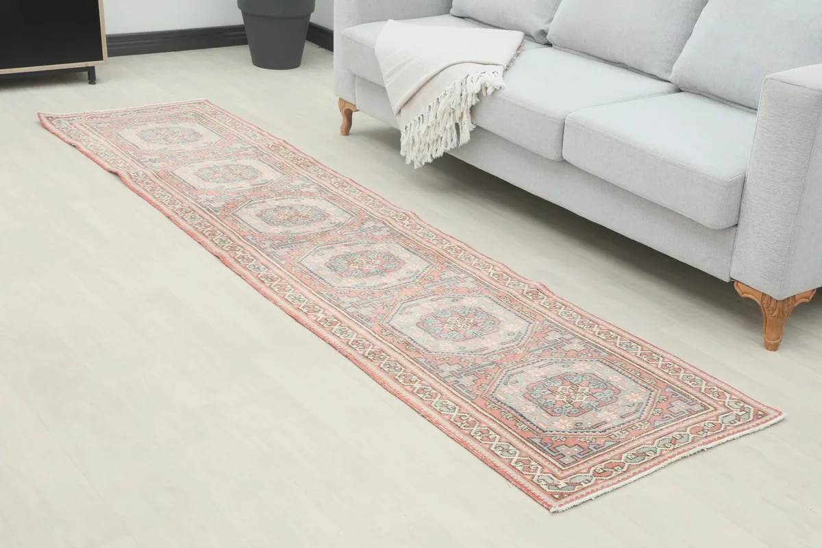 Angled view of the vintage Anatolian runner rug extending from a gray sofa in a contemporary room