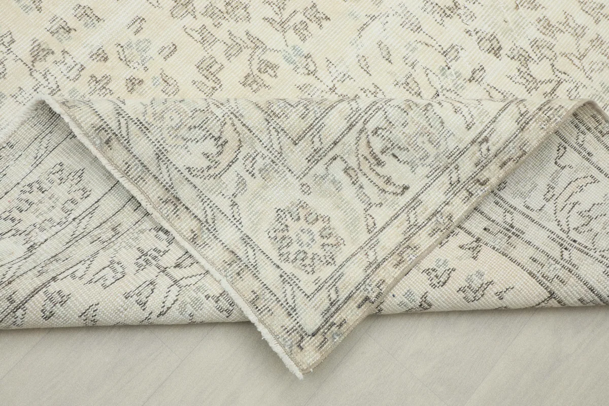 Corner of the Cream Floral Anatolian Rug folded back, revealing the hand-knotted construction and border detail
